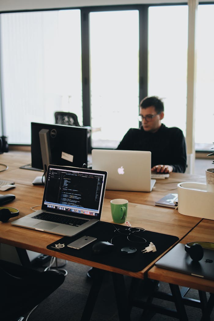 About A web developer working on code in a modern office setting with multiple devices.
